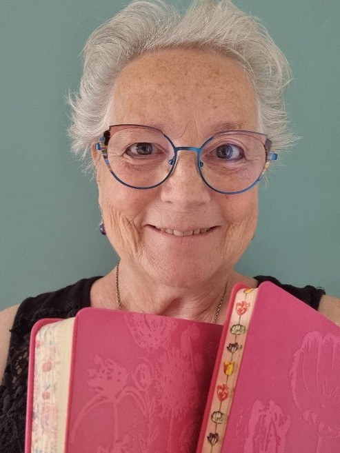 Ellis Vleugels geeft de schrijfworkshop met twee schrijfboekjes in haar handen